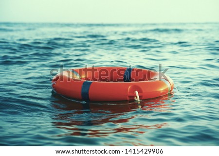 Red lifebuoy in sea on water. Life ring floating on top of water. Life ring in ocean. Toning Royalty-Free Stock Photo #1415429906