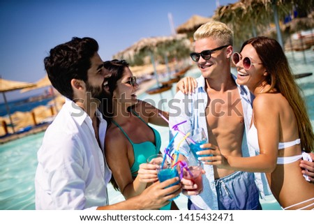 Group of happy friends having fun dancing at swimming pool outdoors