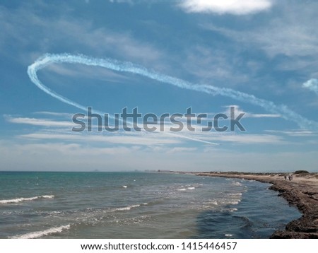 Las Salinas beach in the Mar Menor, Murcia, Spain, with profusion of Poseidonia seaweed in its sand, with the Eagle Patrol, acrobatic flight squadron, doing aerial exercises with their planes,