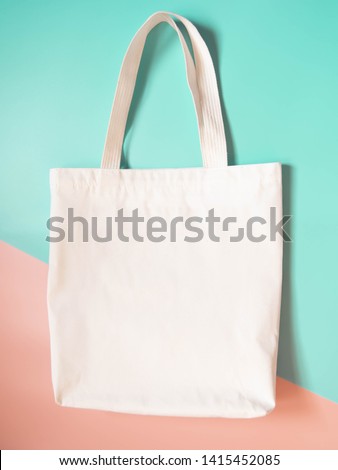 Mock up design bag concept. Blank white tote bag canvas fabric on orange green background. Empty eco bag. Copy space. Vertical.