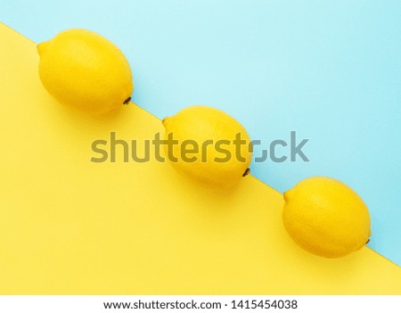Lemons in row on pastel yellow and blue background. Minimal style, summer concept. Flat lay.