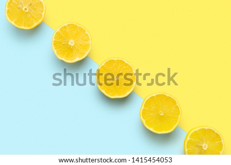 lemon halves in row on pastel yellow and blue background. Minimal summer concept. Flat lay.