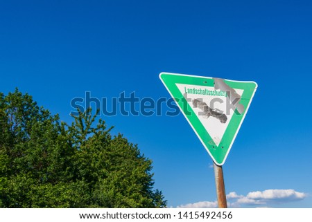 Landschaftsschutzgebiet is Germany words mean Nature preserve. The   rough old nature preserve sign consist of triangular shape with green and white background and eagle symbol at centre   in Germany.