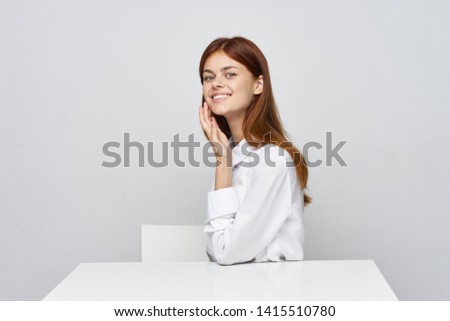 A young woman in a white shirt is sitting at a table in the office            