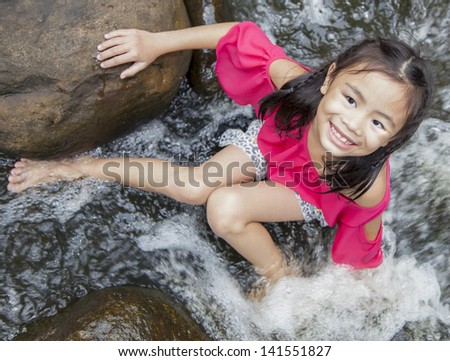 Asian girl sitting near the waterfall
