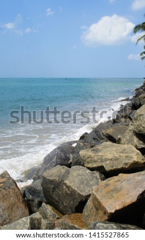 Southern tropical summer ocean coast with rocks and rocks. Lagoon with a yellow sandy beach and azure water.