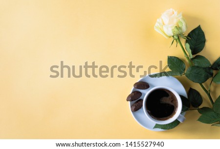 cup of coffee with white rose candy on yellow background