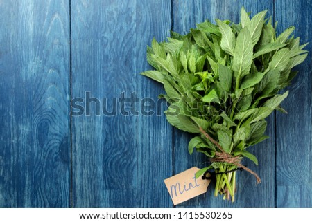 Mint. Leaves and branches of fresh green wild mint and a sign with an inscription on a wooden blue table. top view. space for text
