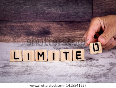 Limited. Word from wooden letters. Marble table and wooden background