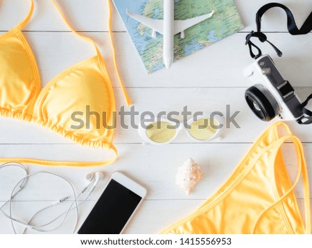top view travel concept with bikini, map, passport, digital camera and travel accessories on white wooden background, Tourist essentials, vintage tone effect.
