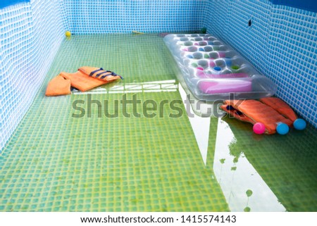 close up dirty garden pool with life jackets inside