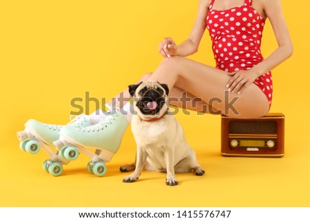 Cute pug dog and woman in roller skates sitting on retro radio receiver against color background
