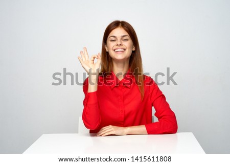 cheerful emotional business woman on the desktop red shirt gray background work computer smile