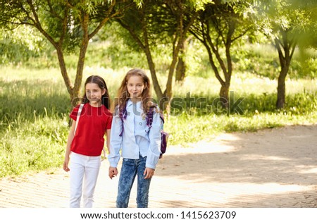 School kids stand embracing in a row outdoors, portrait, sunlight