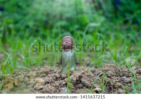 selective focus on chinese ceramic young monk doll stand on ground in garden.Blurred nature background.