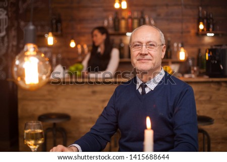 Portrait of nice old man smiling at the camera in a restaurant. Man in his sixties. Adult man.