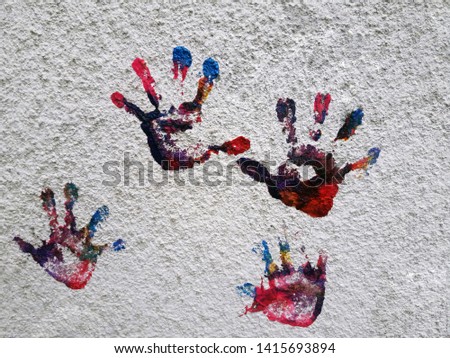 Multiple colored hand prints on white wall background. Hands prints made by children isolated on white background. 