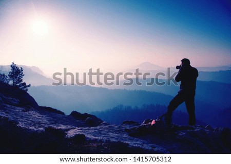 Traveler framing picture with eye on camera viewfinder. Photo enthusiast enjoy work of fall nature on rocky summit.