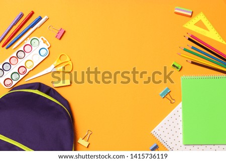 school backpack and school stationery on a colored background top view. Concept back to school.
