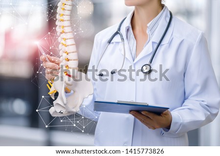 A medical worker shows the spine on blurred background. Royalty-Free Stock Photo #1415773826