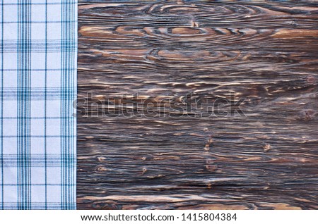 Old dark wooden background. Wooden table with green tea towel in a cage