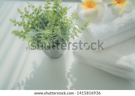 Mockup stack of white towels and houseplant on white table with copy space