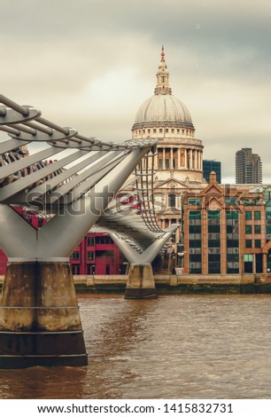 Londoners walking through Millennium Bridge with St.Paul's Cathedral at the background after sunset - London, UK 