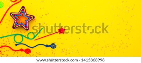 Background of children's holiday flat lay.  Children's birthday. Bright frame for the holiday design of colorful tubes for drinks candles and stars. Confetti on a yellow background. long banner