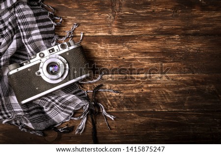 Old retro camera on vintage brown wooden board with black and white checkered scarf. abstract background. Top view.Copy space for text.