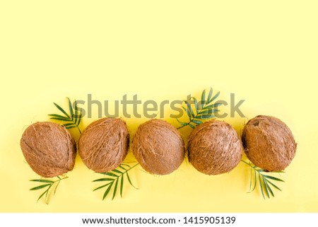 Pattern with coconuts and tropical palm leaves on yellow background. Tropical abstract background. Flat lay, top view.
