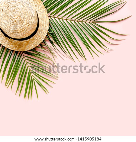 Traveler accessories, tropical palm leaf branches, straw hat on pink background with empty space for text. Travel vacation concept. Summer background. Flat lay, top view.