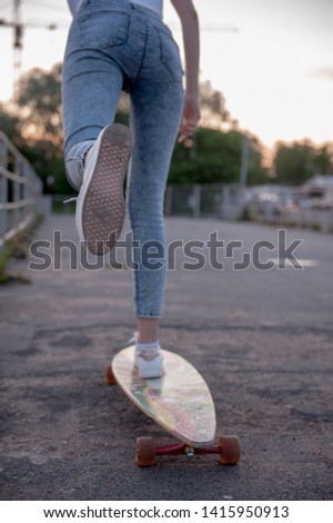 Street sports: A girl pushes off with her foot and rolls on a longboard.