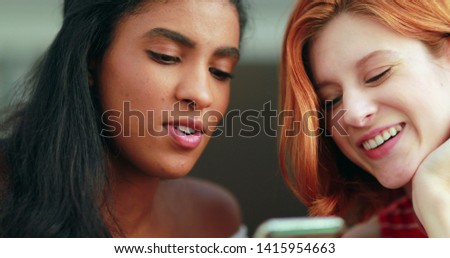 Two racially diverse girls looking at cellphone screen