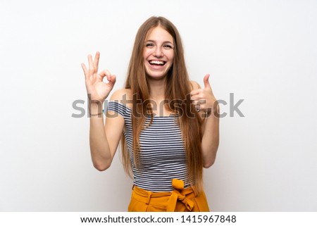 Young woman with long hair over isolated white wall showing ok sign and thumb up gesture