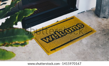 Front door with doormat plants with welcome, written on it