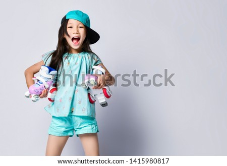 Little asian baby girl kid sitting with roller skates in light blue t-shirt and hat cap happy smiling on white background