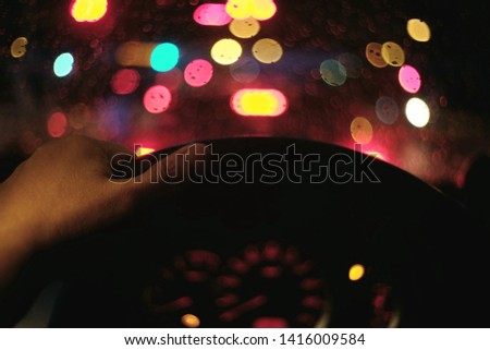 Picture blurring of the hand that forces the steering wheel of the car, driving the car while it rains at dusk