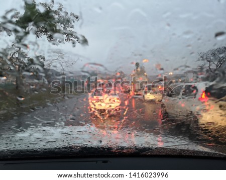 Road view through car window blurry with heavy rain.Driving in rain weather.Raindrops on the windscreen to car. 