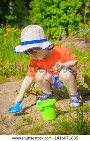A boy with a bucket and a shovel playing in the sand. Children's games. Summer and sand. The boy has a bright photo. The boy plays