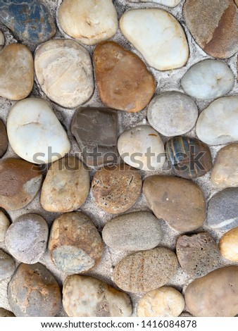 Small river rocks placed on concrete footpath Royalty-Free Stock Photo #1416084878