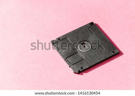 black floppy disk on pink background. retro magnetic storage