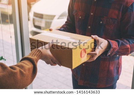 woman receiving parcel box from delivery man at the house's door