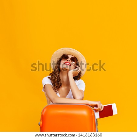 concept of travel. happy woman girl with suitcase and passport on  yellow colored background
