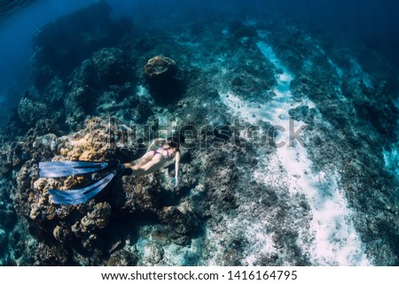 Woman freediver glides underwater with sea turtle. Snorkeling with turtle in blue ocean