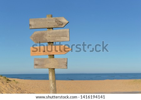 wooden signs on a post in a beach under blue sky 
