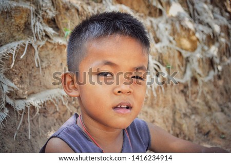 Face of a playful Asian kid winking from the right eye