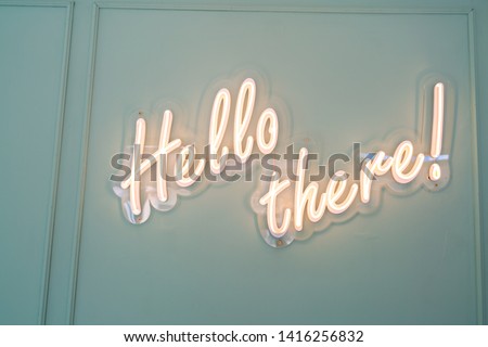 Neon glowing sign with word Hello there and green wall. Royalty-Free Stock Photo #1416256832
