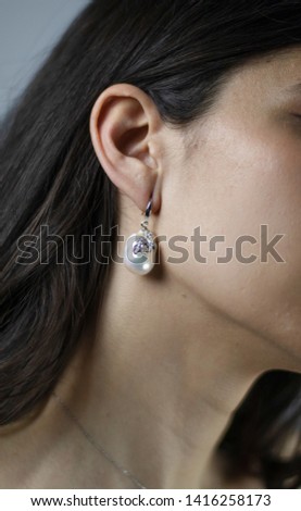 Beautiful earring with a natural baroque pearl of the sea. Ear of young woman.