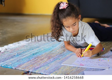 Pretty little girldrawing with pencils on capet at home