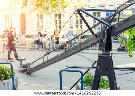 Movie set with professional equipment and media production team on city street. Outdoor film making. Big camera crane with cameraman seat at open air cinema  making scene